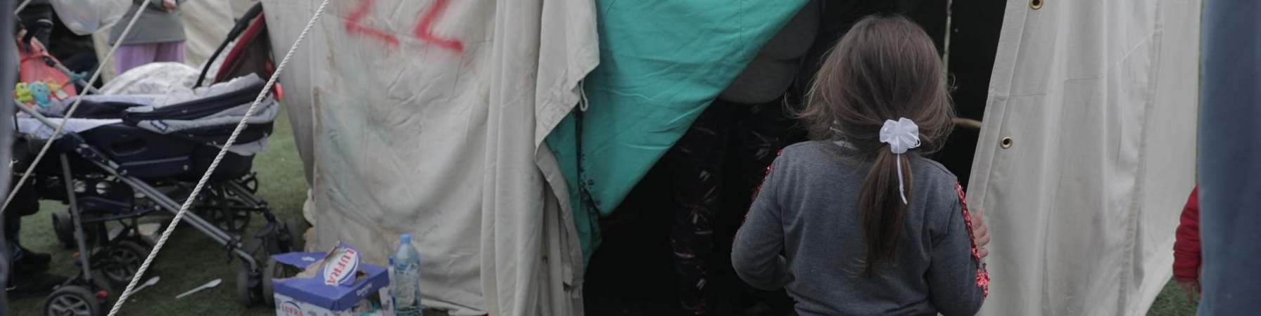 bambina di spalle di fronte a una tenda in accampamento di risposta al terremoto in Albania