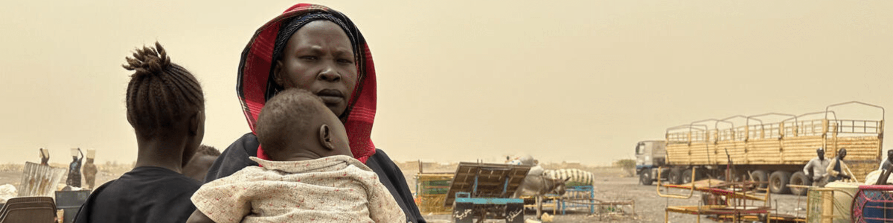 terreno arido in sudan con madre che tiene in braccio il figlio 