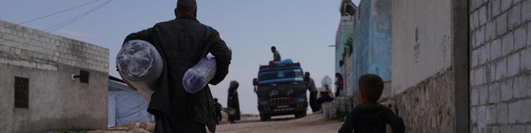 padre e bambino in Siria che trasportano taniche e sacchi dopo il terremoto che ha colpito Turchia e Siria