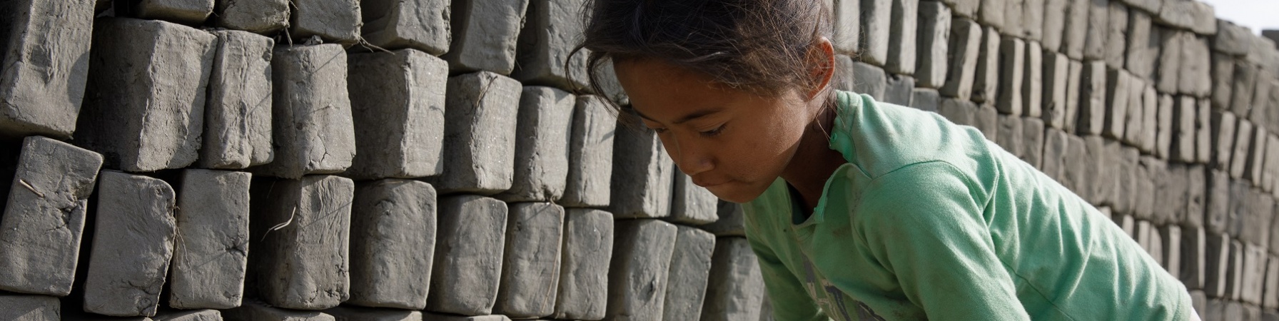 Bambina nepalese sposta mattoni in una fornace di fabbricazione