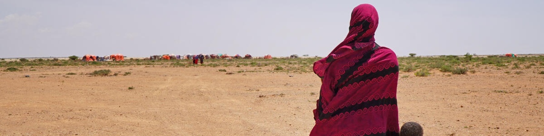donna somala che cammina tenendo per mano un bambino 