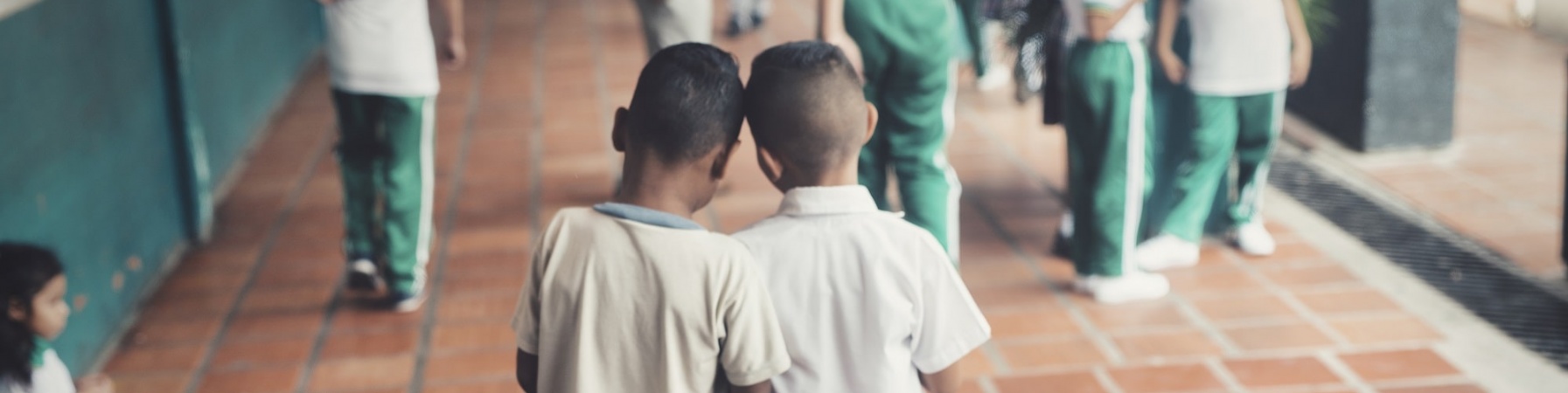 due bambini di spalle vicini che camminano verso un gruppo di bambini e bambine