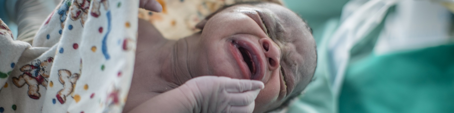 Bambino appena nato in ospedale nella mano con guanto di un medico