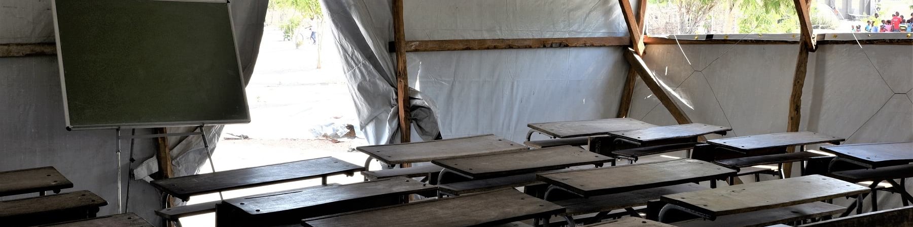 Aula con banchi di scuola e lavagna allestita in un tendone 