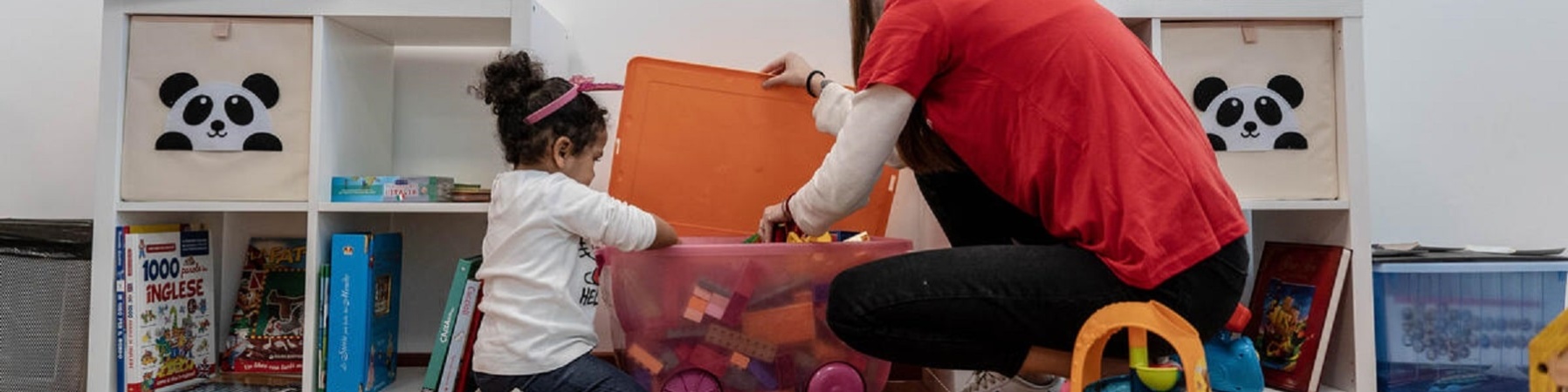 Un bambino svolge attività psicomotorie con il sostegno di una operatrice di Save the Children