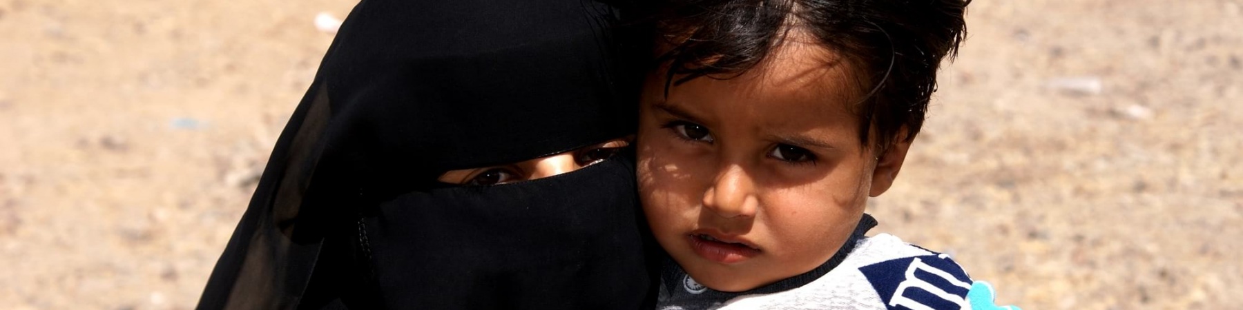 mamma velata con burka tiene in braccio la sua bambina