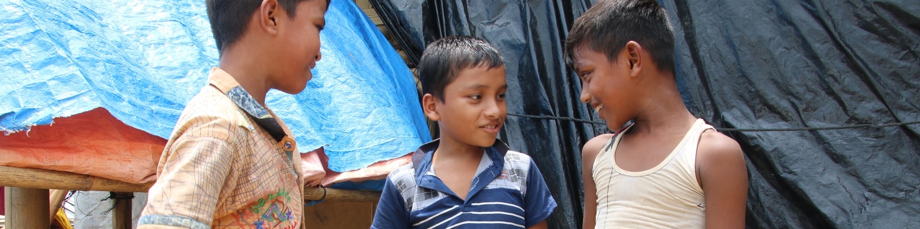 Tre bambini rohingya uno a fianco all altro in piedi parlano tra loro