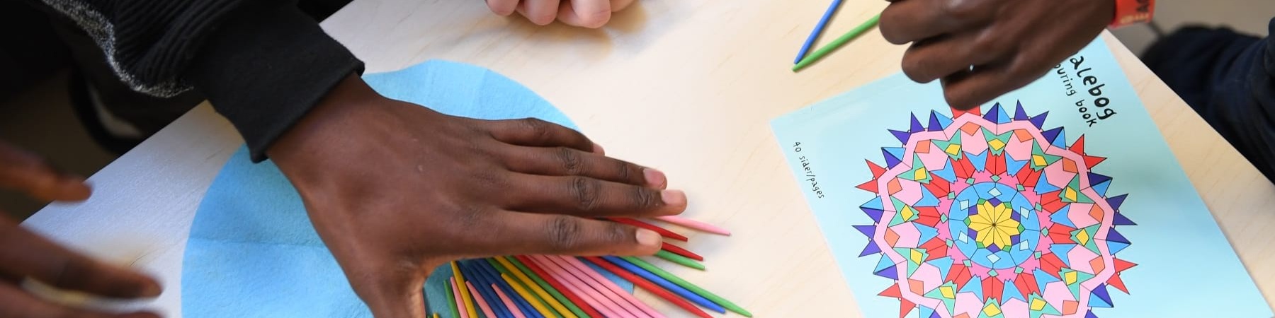 mani di ragazzini prese dall alto colorano un disegno appoggiato sul tavolo