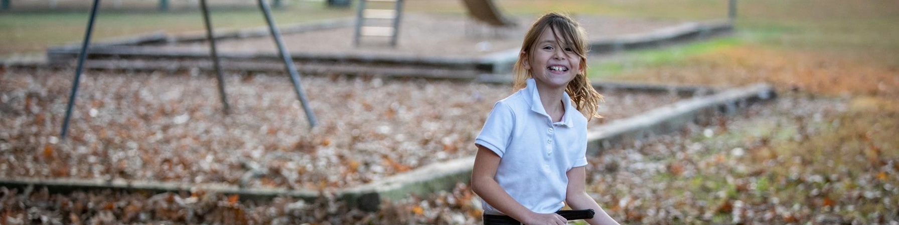 Bambina bionda gioca in un parco con cerchio