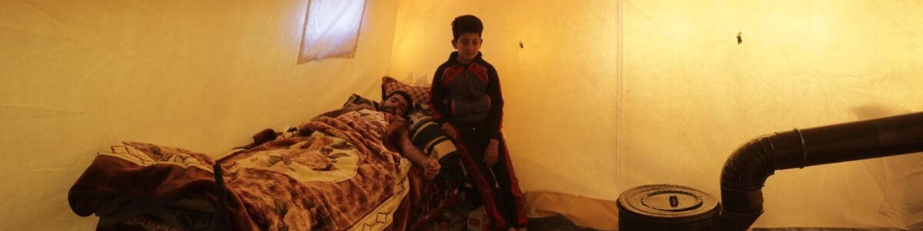 bambino sul letto con il padre in un rifugio dopo il terremoto in turchia e siria