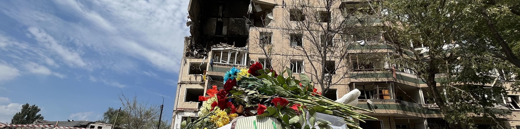 Palazzo distrutto con fiori e bambole in primo piano 