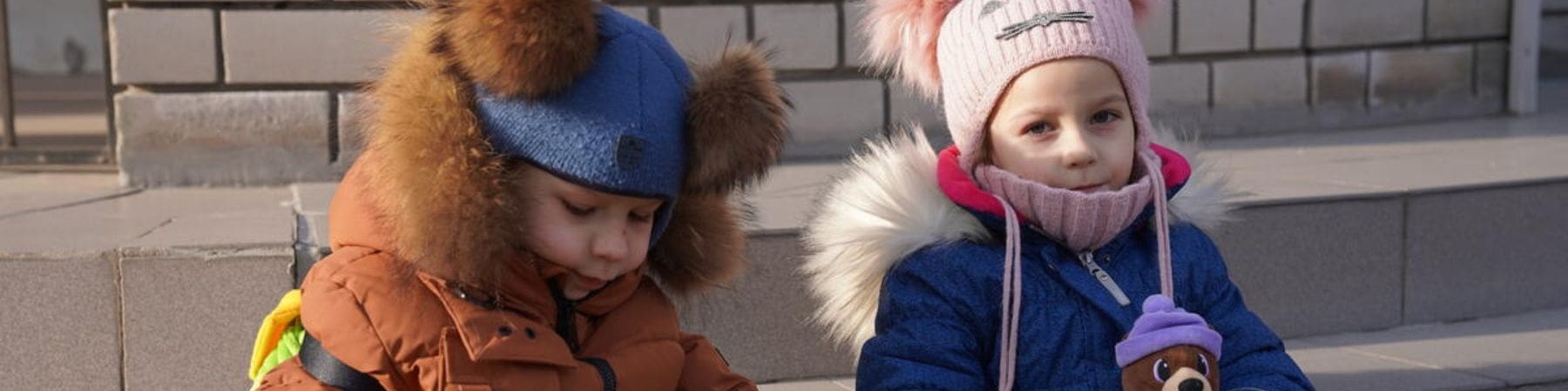 bambina e bambino ucraini seduti accanto con pupazzo in mano