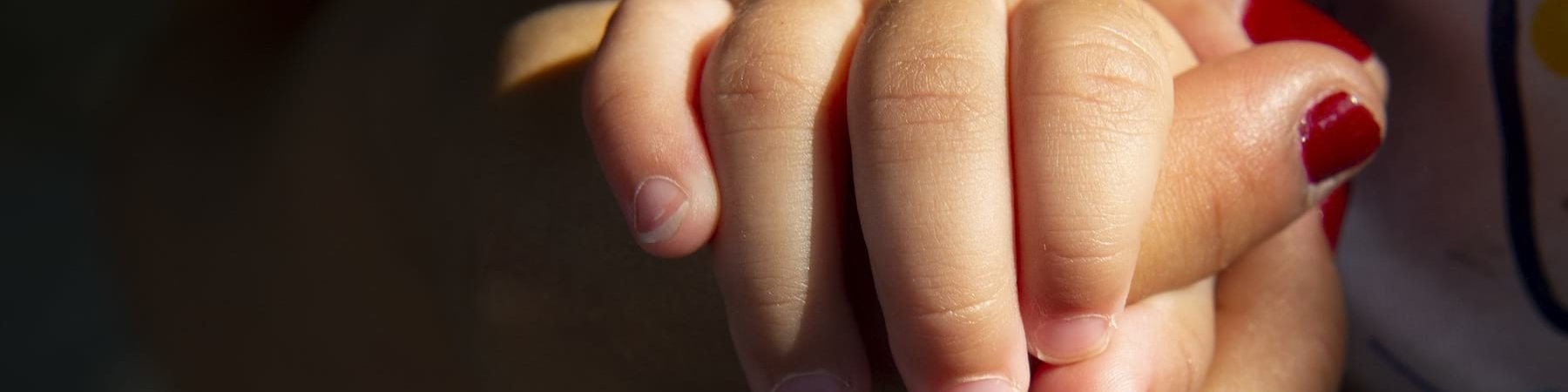 mano di donna con lo smalto rosso tiene la mano di un bambino piccolo