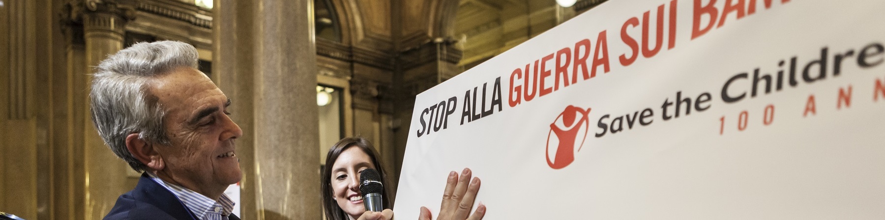 Valerio Neri stampa la sua mano su un cartellone per stop alla guerra sui bambini