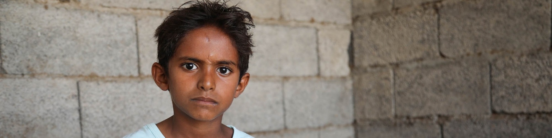 bambino yemenita seduto sul letto con sguardo molto triste