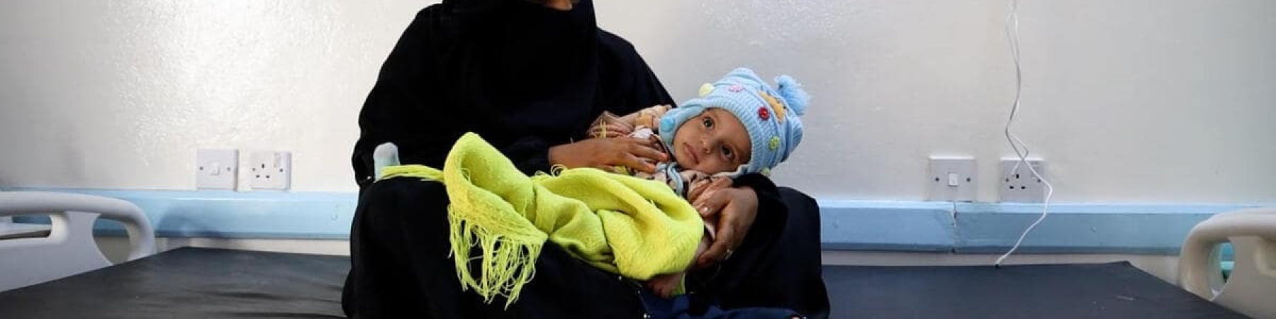 madre che tiene in braccio la sua bambina in un ospedale in Yemen