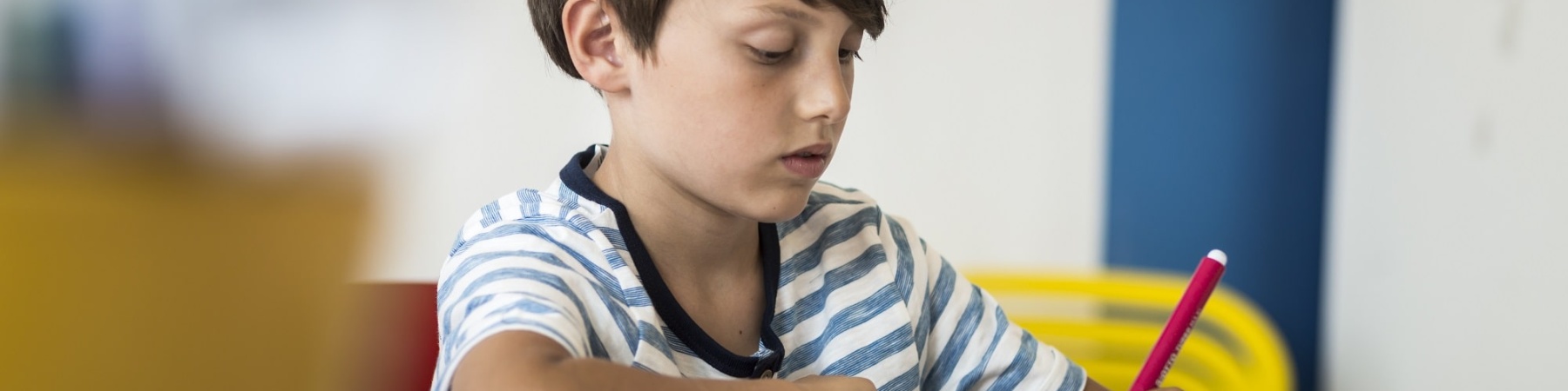 bambino seduto a un banco di scuola mentre disegna