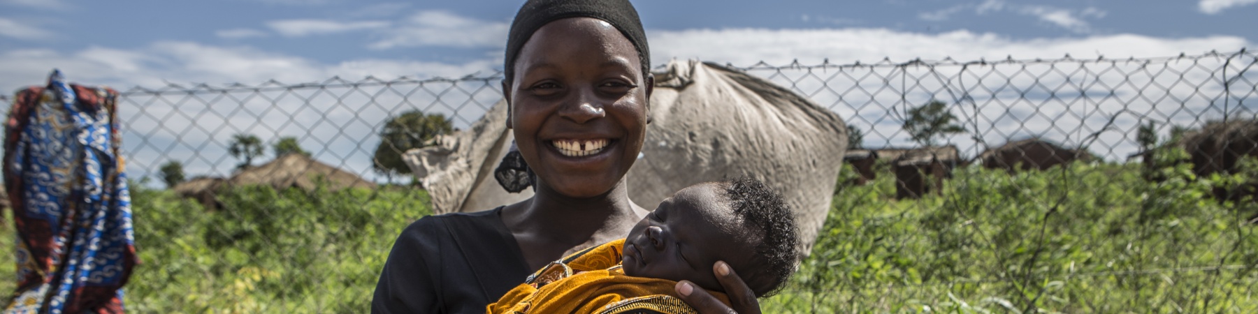 mamma sorridente con bambino in braccio in un campo
