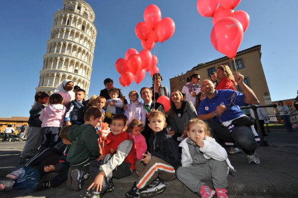 bambini con i palloncini rossi di fronte la torre di pisa
