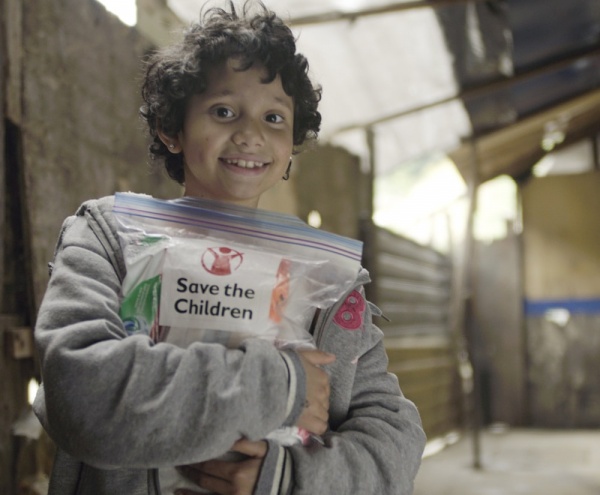 bambino che tiene stretto a se il kit fornito da Save the Children