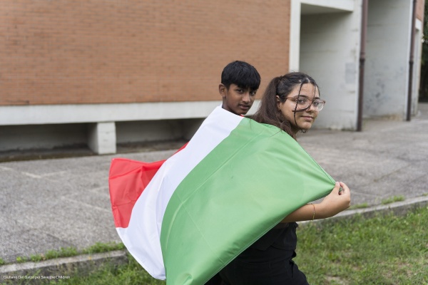 bambina e bambino con bandiera italiana sulle spalle 