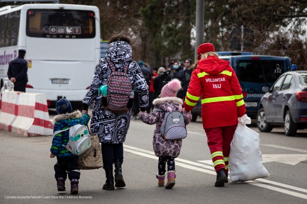 una famiglia di persone cammina in strada e è ripresa di spalle. Sono un uomo una donna e due bambini.