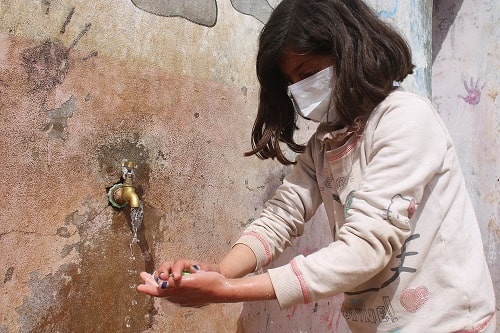 La prevenzione contro il Coronavirus passa anche da un frequente e attendo lavaggio delle mani Una bambina siriana, che indossa una mascherina, si lava le mani per prevenire il contagio di Covid-19