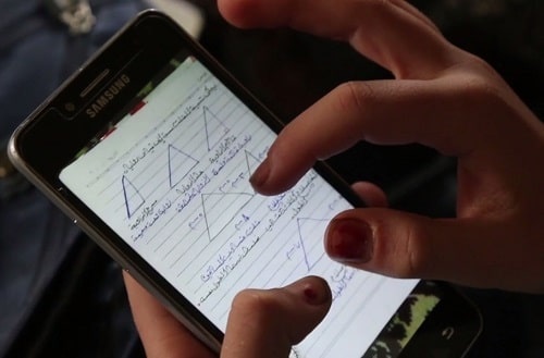 Una bambina siriana fa i compiti con il cellulare Una bambina siriana fa i compiti con il cellulare durante l'emergenza Coronavirus