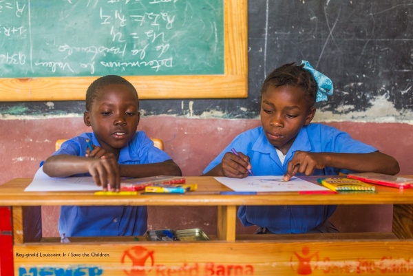 due bambini di Haiti seduti ad un banco nella scuola costruita da save the children