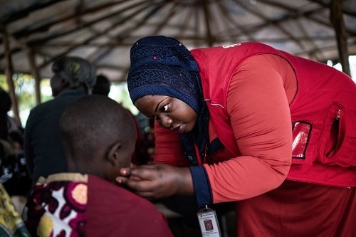 Una operatrice in Uganda controlla lo stato di salute di un bambino Una operatrice in Uganda controlla lo stato di salute di un bambino
