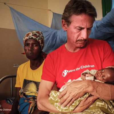 Cesare Bocci che tiene una bambina in braccio durante la visita sul campo nel nostro progetto in Mozambico nel 2016 