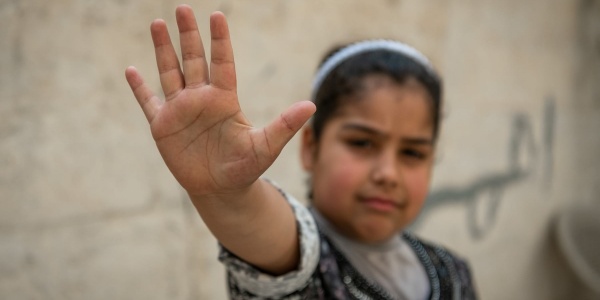 Primo piano di una bambina con la mano davanti facendo gesto di stop
