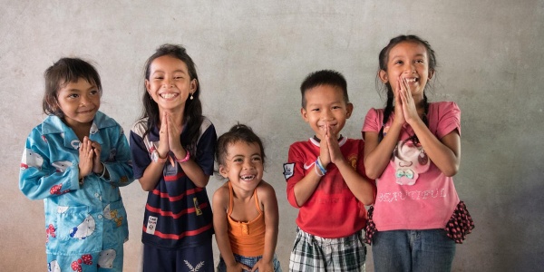 5 bambini cambogiane in piedi con le mani giunte sorridono