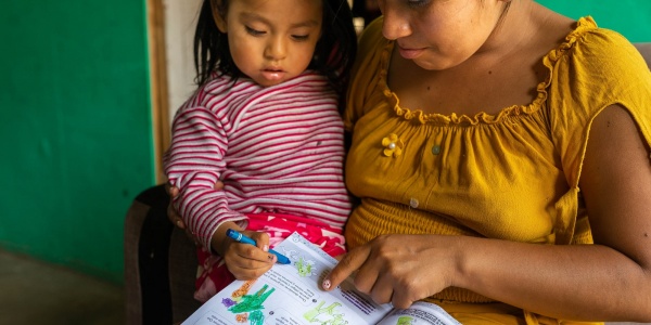 bimba in braccio alla madre mentre colorano insieme un libro da colorare per bambini