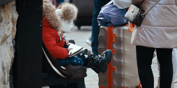 bambino in fuga dalla guerra seduto su una valigia