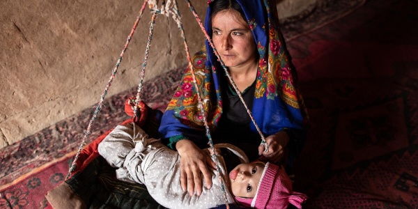 madre afgana con bambino malnutrito su una bilancia