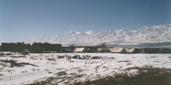 tende di un campo profughi su un campo di neve ai piedi di alte montagne innevate in afghanistan