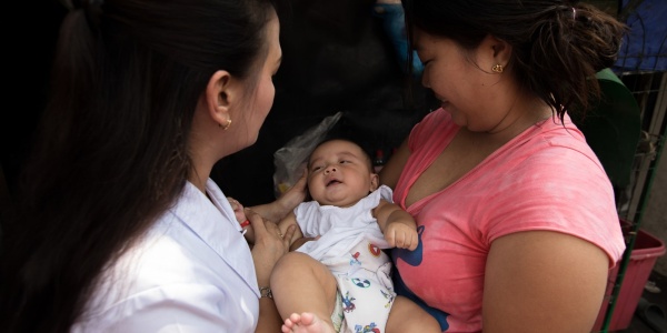 mamma con in braccio la sua bimba neonata insieme a un operatrice di Save the Children