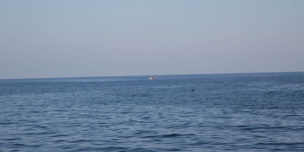 orizzonte tra cielo e mare, in lontananza una piccola imbarcazione