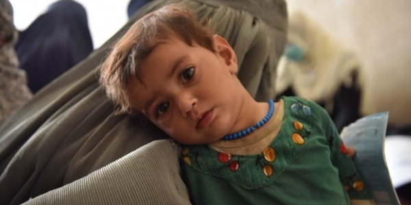 bambino afghano di due anni con camicia verde guarda in camera