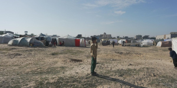 Ragazzo in piedi davanti alle tende a Gaza