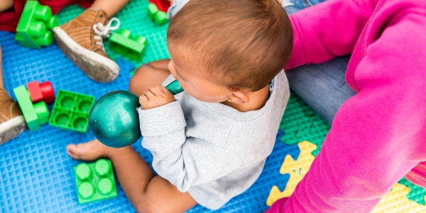 bimbo seduto su un tappeto colorato di gomma che gioca insieme alla sua mamma