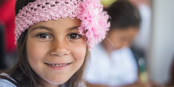 Primo piano bambina sorridente con fascia rosa in testa