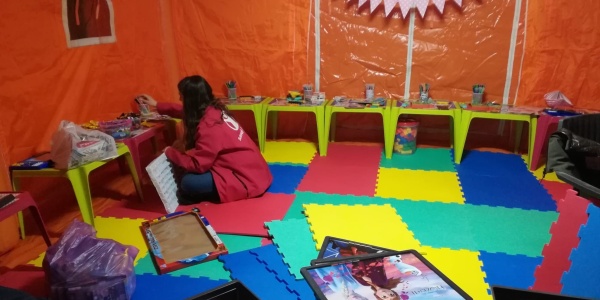 Interno di uno spazio a misura di bambino Save the Children in Romania dove un operatrice sta mettendo a posto i giochi seduta a terra.
