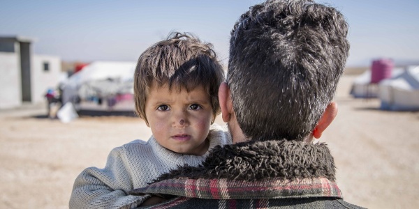 bambina siriana in braccio al papà di spalle