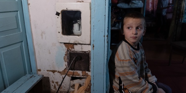 bambino ucraino seduto in camera che guarda alle sue spalle