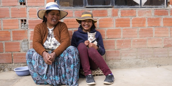 Donna e bambina in Bolivia sedute per terra, sorridenti