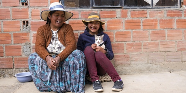 Donna e bambina in Bolivia sedute per terra, sorridenti