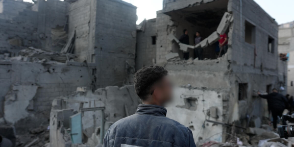 uomo di spalle di fronte ad un palazzo distrutto a Gaza
