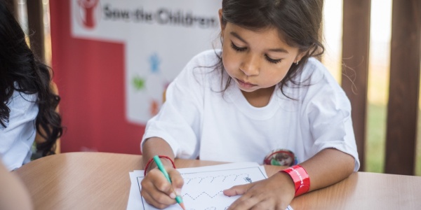 bambina seduta a un tavolo mentre fa i compiti